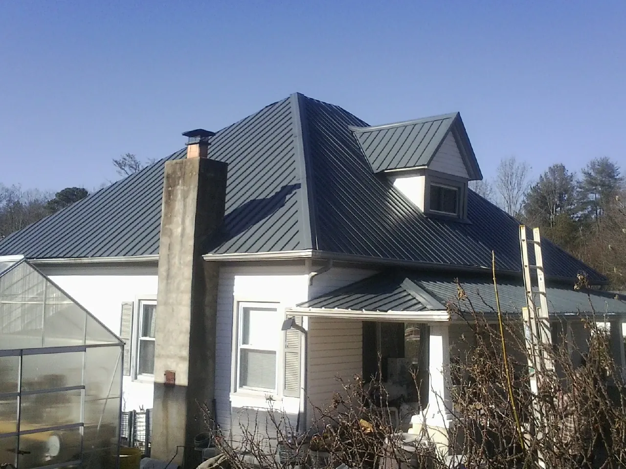 Dark blue standing seam metal roof on a white farmhouse with dormer — Slate & Tile Roof Repair by Roofing Brothers in Juliaetta
