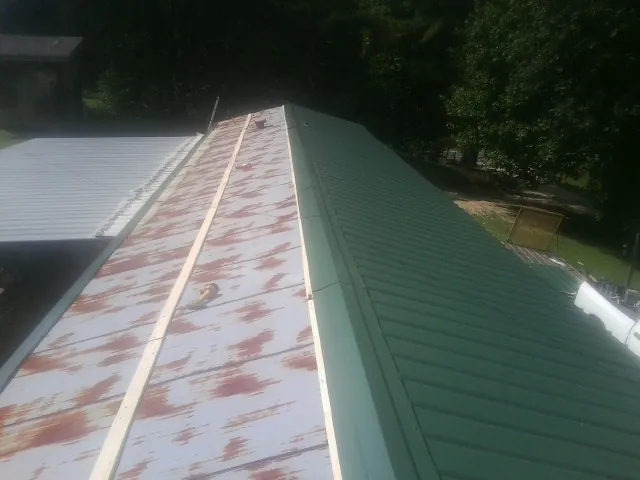 Old rusted panels beside newly installed green metal roofing — Wind Damage Roof Repair by Roofing Brothers in Juliaetta