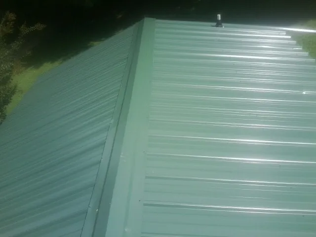 New green metal panels meeting at the ridge of a roof — Flat Roof Repair work by our crew in Juliaetta