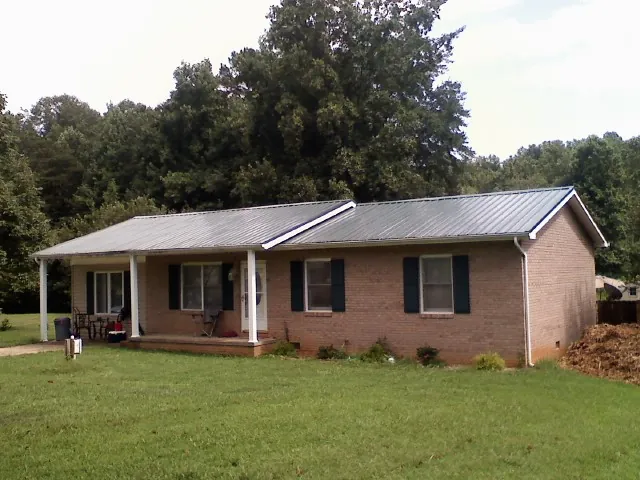 Gray metal roof on a brick ranch house with a side carport in Juliaetta