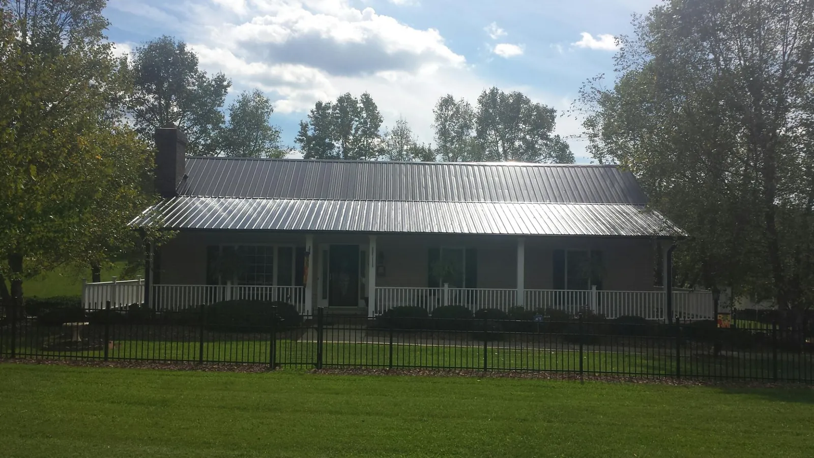 Gray metal roof on a brick ranch with a full width front porch — Gutter Guard Installation work by our crew in Juliaetta